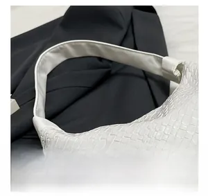 Close-up of the intricate white woven leather texture and wide strap on the shoulder bag