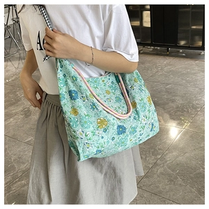 Floral canvas tote bag with drawstring detail and mint green base color worn by model
