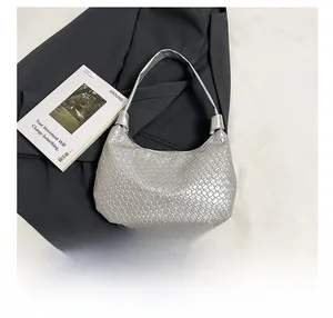 Detail of silver woven hobo bag showing metallic texture and size comparison with phone