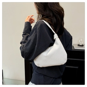 Side view of white woven shoulder bag with minimalist crescent shape and leather texture
