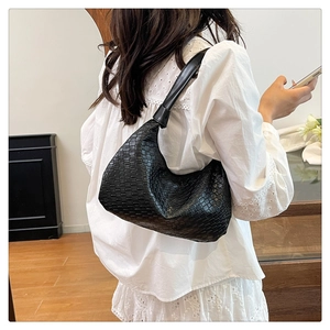 Close-up of black woven hobo bag on model's shoulder showing textured leather pattern