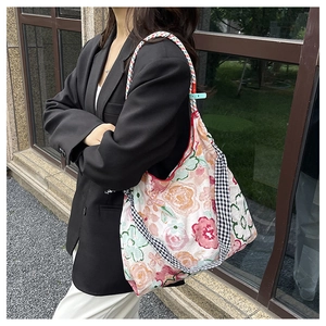 Detail of floral canvas tote bag featuring unique plaid straps and woven rope handles