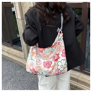 Floral canvas tote bag with woven straps and bow detail worn by model outdoors