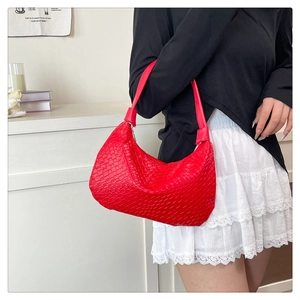 Detailed view of the red woven texture and crescent shape of this stylish shoulder bag