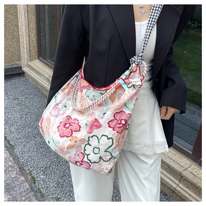 Close-up of colorful floral canvas hobo bag with artistic woven braided shoulder straps