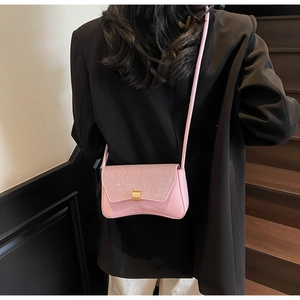 Detail of pink glitter baguette bag with crescent base and golden square buckle on shoulder