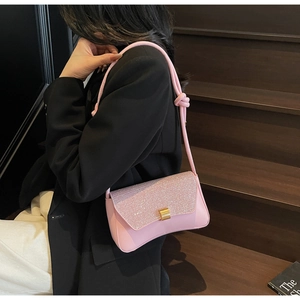 Detail of pink baguette bag with sequined flap and knotted shoulder strap in a lifestyle shot