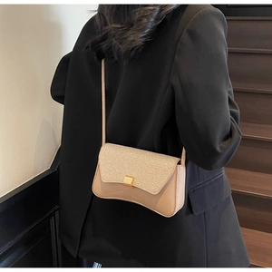 Détail du sac à bandoulière beige élégant porté par un mannequin dans un décor moderne