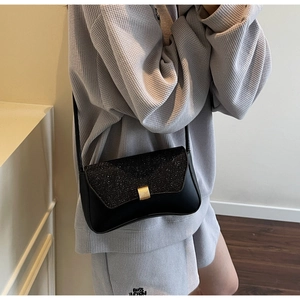 Detail view of black glitter crossbody bag with gold hardware buckle and leather strap