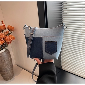 Detail der blauen Denim-Patchwork-Umhängetasche mit Ziertaschen und Metallreißverschluss