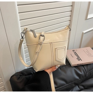 Detail der cremefarbenen Ledertasche mit Taschendesign und braunen Kontrastnähten