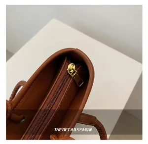 Close-up of premium gold-tone metal zipper and precise stitching on brown woven bag