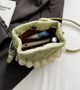 Vue de dessus d'un sac seau matelassé vert clair montrant l'intérieur et les perles