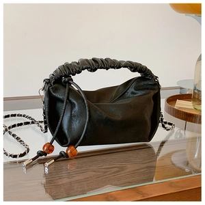 Détail du sac plissé noir avec cordon en perles d'ambre et bandoulière argentée
