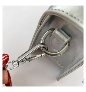 Close-up of silver leather mini bag showing metallic lobster clasp and D-ring details