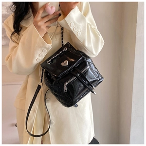 Detail of black quilted backpack featuring heart-shaped silver hardware and chain straps