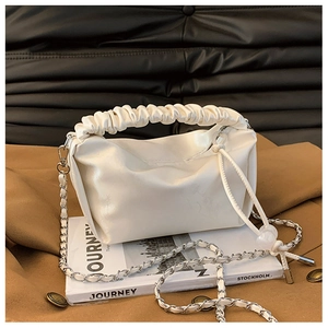 Détail du sac crème avec poignée plissée et bandoulière en chaîne métallique dorée