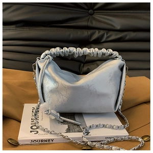 Détail du sac à main plissé bleu clair avec finition satinée et motifs de feuilles