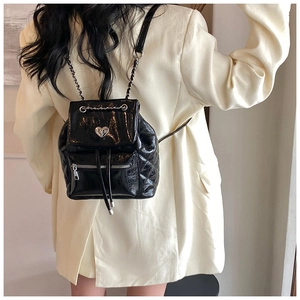 Close-up of shiny black mini backpack featuring a silver heart-shaped twist lock buckle