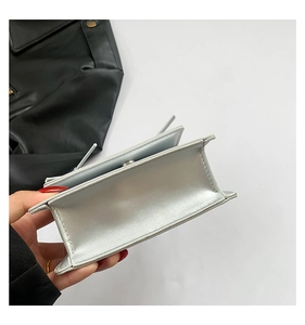 Detail of silver metallic handbag showing magnetic closure and interior compartment