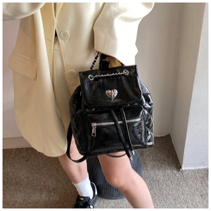 Detail of glossy black patent leather backpack featuring heart-shaped metal twist lock