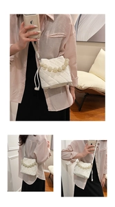 Détail du sac seau matelassé blanc avec poignée en perles et bandoulière élégante