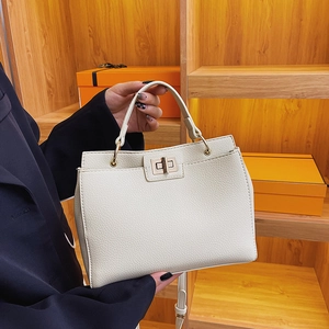 Vintage cream leather tote bag with gold lock and top handle shown on a wooden stand