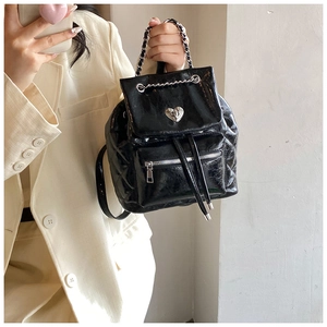 Detail of glossy quilted backpack featuring heart-shaped metal lock and chain handle