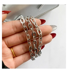 Detailed view of glossy silver metal cable chain strap held by hand with red nails
