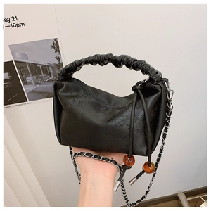 Détail du sac à main noir plissé avec texture vintage, perles d'ambre et chaîne argentée