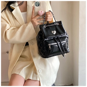 Detail of black quilted patent leather backpack with silver heart-shaped twist lock buckle
