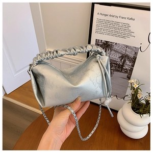 Détail du sac à main argenté avec poignée plissée et chaîne métallique élégante