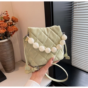 Détail du sac seau matelassé vert clair avec élégante poignée en grosses perles blanches