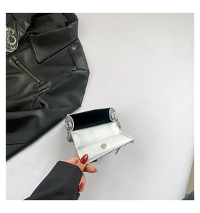 Detail view of mini metallic chain bag showing interior black lining and snap closure