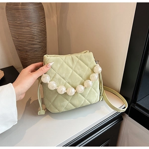 Détail du sac seau matelassé vert clair avec poignée en perles marbrées et cordon