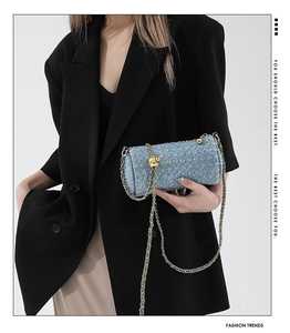 Détail du sac cylindre matelassé bleu clair avec chaîne dorée et finition pailletée
