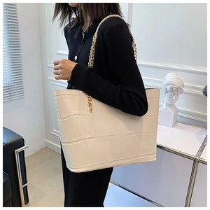 Crocodile pattern tote bag with gold chain strap shown on model in light luxury setting