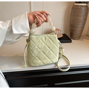 Détail du sac seau matelassé vert clair avec grande poignée perlée crème et cordon