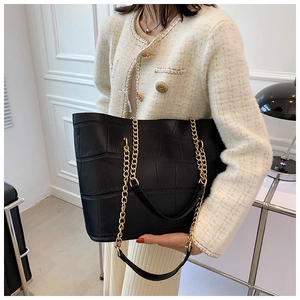 Close-up of black crocodile pattern tote bag with gold metal chain shoulder strap