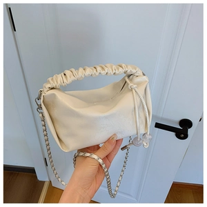 Détail du sac à main plissé crème avec bandoulière chaîne argentée et cordons perlés