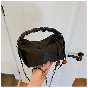 Détail du sac en cuir noir gaufré avec poignée froncée et perles d'ambre décoratives