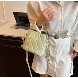 Détail du sac seau matelassé avec poignée en perles marbrées et cordons de serrage verts