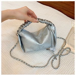 Détail du sac à main argenté métallisé avec motif floral, poignée plissée et chaîne