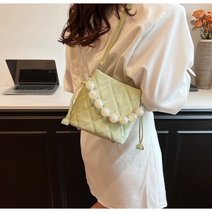 Gros plan du sac seau matelassé vert clair avec poignée en perles et cordon de serrage