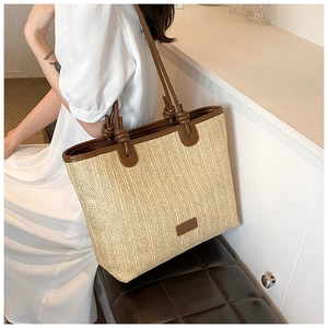 Detail of hand-woven straw tote bag with brown leather straps and knotted accents