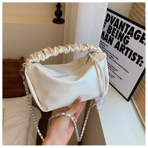 Détail du sac à main beige avec poignée plissée, texture florale et chaîne argentée