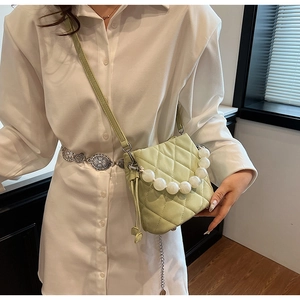 Détail du sac seau matelassé vert clair avec une grande poignée en chaîne de perles