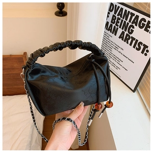 Détail de la poignée plissée et du cordon à perles ambrées sur le sac à main noir imprimé
