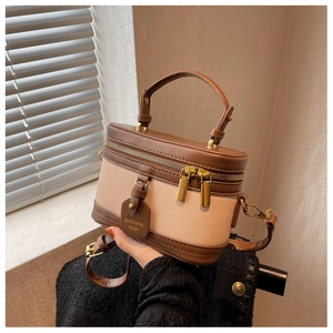 Détail du sac seau vintage en cuir marron, toile beige et doubles fermetures éclair dorées