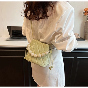 Détail du sac seau matelassé vert clair avec grande poignée en perles et texture velours